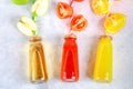 Bottles with fresh orange, apple, tomato juice and colored tubules on a gray concrete table. Fruits and vegetables around. Top vie Royalty Free Stock Photo