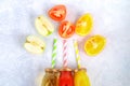 Bottles with fresh orange, apple, tomato juice and colored tubules on a gray concrete table. Fruits and vegetables around. Top vie Royalty Free Stock Photo