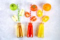 Bottles with fresh orange, apple, tomato juice and colored tubules on a gray concrete table. Fruits and vegetables around. Top vie Royalty Free Stock Photo