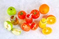 Bottles with fresh orange, apple, tomato juice and colored tubules on a gray concrete table. Top view. Royalty Free Stock Photo