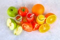 Bottles with fresh orange, apple, tomato juice and colored tubules on a gray concrete table. Top view. Royalty Free Stock Photo