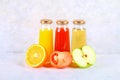 Bottles with fresh orange, apple, tomato juice on a gray concrete table. Royalty Free Stock Photo