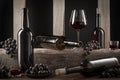 Bottles and glasses of Spanish red wine and grapes on wooden base on black background