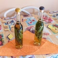 Bottles of homemade flavored grappa with Rosemary and Sage on the table