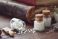 Bottles of homeopathic globules and old books. Homeopathy medicine concept