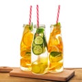 Bottles of infused detox water with lemon, orange, lime, twig mint, cucumber, ginger and straws on wooden background isolated, Royalty Free Stock Photo