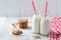 Two bottles of milk with straws and chocolate chip cookies on wooden background Royalty Free Stock Photo