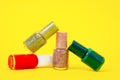 Bottles of multicolored matte and shiny nail polishes with shimmering effect on yellow background, front view, copy