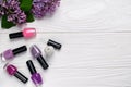 Bottles of nail polish on white wooden background with spring flowers top view with space for text Royalty Free Stock Photo