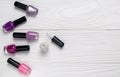 Bottles of nail polish on white wooden background top view with space for text Royalty Free Stock Photo