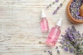 Bottles with natural lavender oil and flowers on white wooden table, flat lay Royalty Free Stock Photo