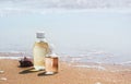 Bottles with oil essence and shell in the sea waves. Spa and wellness setting on sand and wave background.   Manicure and Pedicure Royalty Free Stock Photo