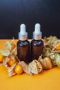 Bottles with physalis oil  and fresh  fruit  on orange Royalty Free Stock Photo