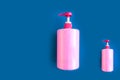 Bottles with pink dishwashing liquid on blue background. Minimal concept. Royalty Free Stock Photo