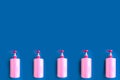 Bottles with pink dishwashing liquid on blue background. Minimal concept. Royalty Free Stock Photo