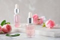 Bottles with rose essential oil and flowers on marble Royalty Free Stock Photo