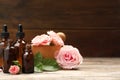 Bottles of rose essential oil and flowers on wooden table Royalty Free Stock Photo