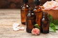 Bottles of rose essential oil and flowers on wooden table Royalty Free Stock Photo