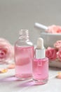 Bottles of rose essential oil and fresh flowers on table Royalty Free Stock Photo