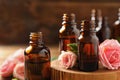 Bottles of rose essential oil and fresh flowers on table Royalty Free Stock Photo