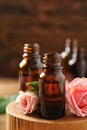 Bottles of rose essential oil and fresh flowers on table, closeup Royalty Free Stock Photo