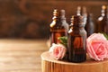 Bottles of rose essential oil and fresh flowers on table, closeup Royalty Free Stock Photo