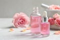 Bottles of rose essential oil and fresh flowers on table Royalty Free Stock Photo