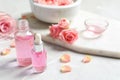 Bottles of rose essential oil and fresh flowers on table Royalty Free Stock Photo