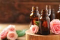 Bottles of rose essential oil and fresh flowers on table. Space for text Royalty Free Stock Photo