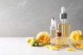 Bottles of rose essential oil and fresh flowers on table Royalty Free Stock Photo