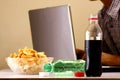 Bottles of softdrinks or soda, chips and man working on a laptop computer in the background Royalty Free Stock Photo