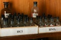 Bottles with solutions of HCl and HNO3 on the shelf of the chemical cabinet