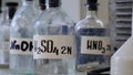 Bottles of solutions stored on shelf in laboratory. Bottles with chemical solutions of NaOH, H2so4 and HNO3. Sulfuric
