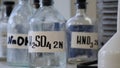 Bottles of solutions stored on shelf in laboratory. Bottles with chemical solutions of NaOH, H2so4 and HNO3. Sulfuric