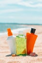 Bottles of sun protection lotion, aloe soothing gel from sun burn, seashells in sand on the beach with sparkling sea in Royalty Free Stock Photo