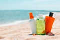 Bottles of sun protection lotion, aloe soothing gel from sun burn, seashells in sand on the beach with sparkling sea in Royalty Free Stock Photo