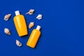 Bottles with sunblock cosmetics and seashells on dark blue background Royalty Free Stock Photo