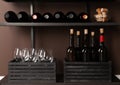 Bottles of wine, corks and glasses on rack near brown wall Royalty Free Stock Photo