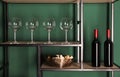 Bottles of wine, corks and glasses on rack near green wall Royalty Free Stock Photo