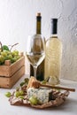 Bottles of wine with ripe grapes and cheese on white table Royalty Free Stock Photo