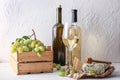 Bottles of wine with ripe grapes and cheese on white table Royalty Free Stock Photo