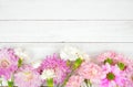 Bottom border of pink and purple flowers against a white wood background Royalty Free Stock Photo