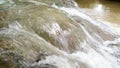 The bottom corner of the waterfall flows over brown rocks down to the river.