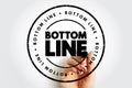 BOTTOM LINE stamp featuring a distressed circular border and repeated text around the ring, shown with a hand holding a marker, Royalty Free Stock Photo