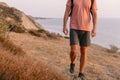 Bottom part of man with backpack walking on sea coastline with warm sun light Royalty Free Stock Photo