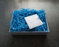 Opened White Box with Blue Crinkled Straw with Small White Envelope