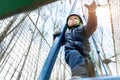 Bottom POV view brave courage little toddler child boy wear safety equipment helmet enjoy passing obstacle course forest
