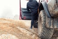 Bottom POV view male person driver open door of 4x4 awd suv vehicle on dirt gravel unpaved road in autumn at misty Royalty Free Stock Photo