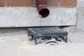 The bottom of a rainwater pipe, downpipe shoe that sends water to the drainage system