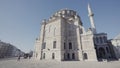 Bottom rear view of a giant muslim mosque on blue sky background. Action. Massive historic building and people walking